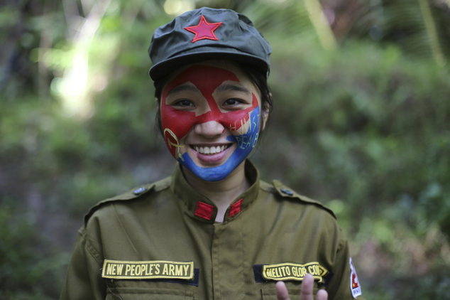 In this photo taken Nov. 23, 2016, a 24-year-old New People's Army guerrilla, who uses the nom de guerre Comrade Katryn, smiles as she talks to reporters at a rebel encampment tucked in the harsh wilderness of the Sierra Madre mountains southeast of Manila, Philippines. Communist guerrillas warn that a peace deal with President Rodrigo Duterte's government is unlikely if he won't end the Philippines' treaty alliance with the United States and resist control by other countries. (AP Photo/Aaron Favila)